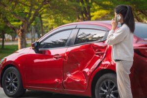 A woman examining the damage on her car after an accident with a Lyft driver